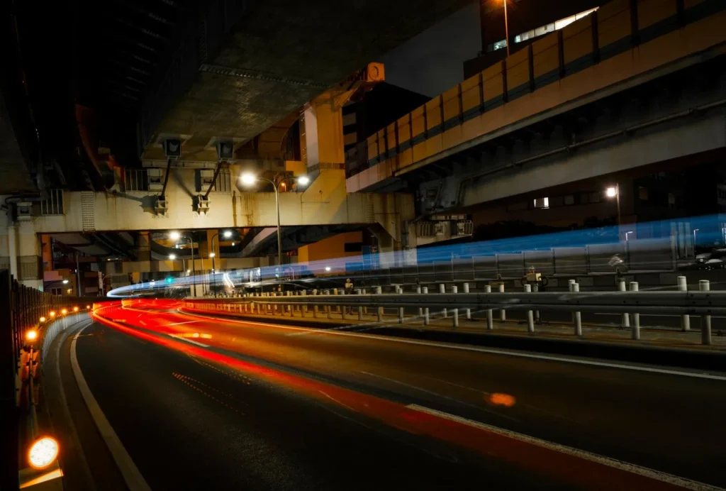Long-exposure photo of urban highway at night with red and blue light trails under overpasses.