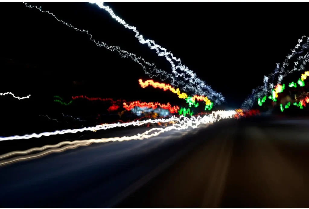 Blurred colorful light streaks against a dark background, resembling a nighttime cityscape in motion.