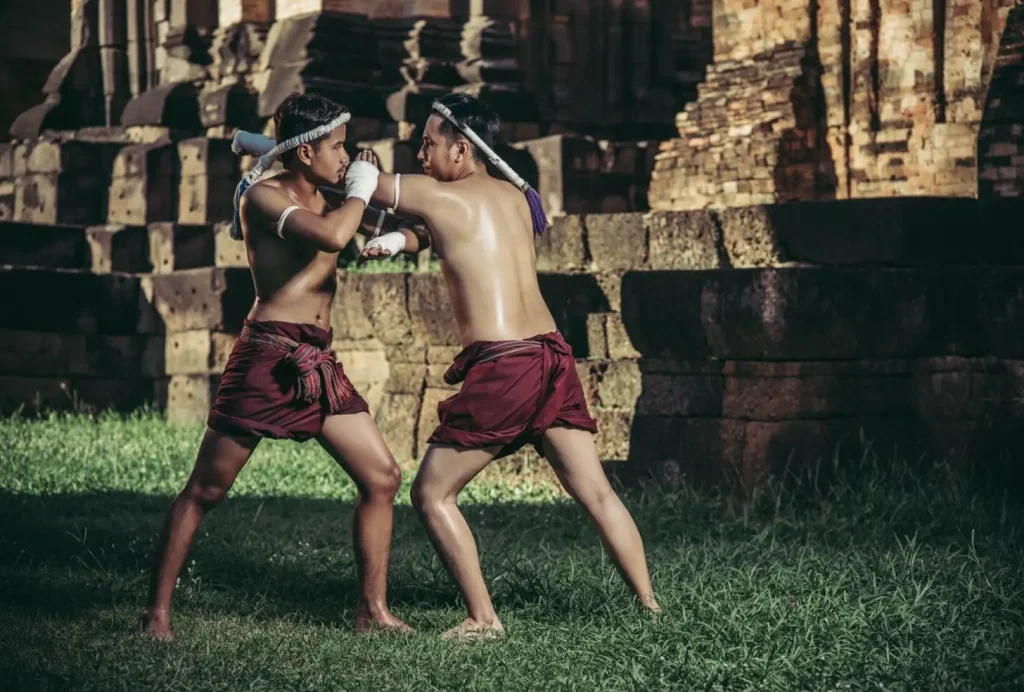 Two men practicing martial arts in traditional attire near ancient stone ruins.