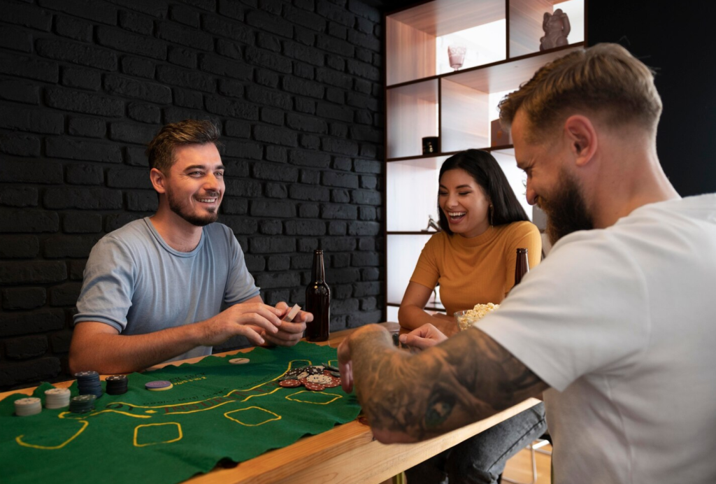 Three friends playing poker at a table, laughing and enjoying drinks and snacks in a cozy room.